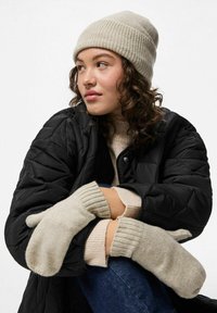 Vaaleanharmaa neulottu myssy ja lapaset; tikattu musta takki; resorineulepusero. Pehmeitä tekstuureja, neutraaleja värejä, rento talviasu.