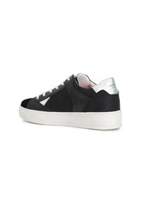 Zapatilla de cuero negra con detalles plateados y suela blanca. Presenta una puntera redonda, cordones planos y un cuello acolchado. Detalle del logotipo visible en el lateral.
