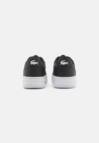 Schwarze Leder-Sneaker mit weißen Gummisohlen. Merkmale ein Lacoste-Logo an der Ferse und ein glatt strukturiertes Obermaterial. Minimalistisches Design.