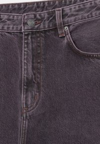 Dunkelviolette Denim-Jeans mit kontrastierenden braunen Nähten, metallischem Knopfverschluss und standardmäßigen Taschendetails. Glatte Textur.