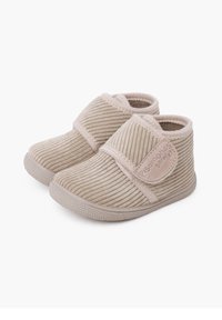 Beige peuterslippers met ribbenstof, klittenbandsluiting, ronde neus en een getextureerde rubberen zool voor grip. Accenten met subtiele branding.