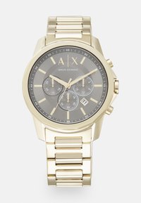 Reloj de acero inoxidable con tono dorado, con un dial gris oscuro, tres sub-diales, marcadores dorados y una pantalla de fecha. Presenta un diseño de pulsera con eslabones.