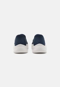 Scarpe slip-on in maglia blu con superficie testurizzata, suola bianca a contrasto e forma arrotondata, progettate per comfort e flessibilità.