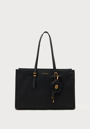 Sort Michael Kors tote taske med to håndtag, gyldent hardware og en hængende sort blomst charm med MK-logo detaljer.