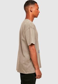 Jasnoszary, oversize t-shirt z miękkiej bawełny, z okrągłym dekoltem, krótkimi rękawami i subtelną, wyblakłą teksturą. Prosty design bez dodatkowych detali.