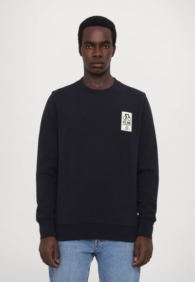 Sweatshirt marine avec col ras du cou, poignets et ourlet côtelés, présentant une étiquette blanche sur la poitrine gauche avec des graphiques de bicyclettes et du texte.