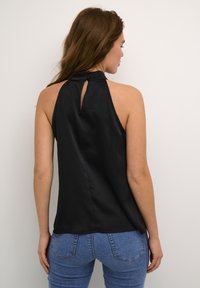 Black halter top with a keyhole detail at the back, featuring a smooth texture and a relaxed fit, paired with blue denim jeans.
