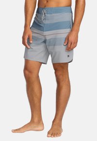 Pánske plavky vo svetlo sivej farbe s horizontálnymi modrými pruhmi, s opaskom na stiahnutie a hladkým, rýchloschnúcim materiálom.