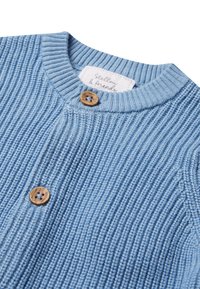 Cardigan à côtes bleu clair avec un col rond, doté de boutons en bois et d'une étiquette inscrite "Stellou & Friends". Texture douce évidente.
