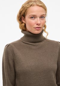 Pulover bej cu guler înalt, dintr-un tricot cu model în riburi, având o croială lejeră, cu o textură subtilă și mâneci lungi.