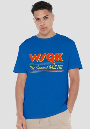 Blue cotton t-shirt with short sleeves, featuring bold yellow and red text "WSQK The Squawk 94.5 FM" across the front.