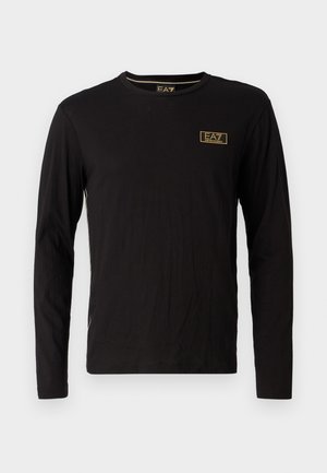T-shirt nero a maniche lunghe in cotone, con scollo rotondo, un piccolo logo dorato sul petto e accenti laterali a contrasto.