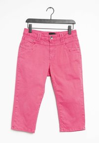 Pantalons roses coupés en coton, dotés de deux poches avant, d'une fermeture à bouton et de coutures piquées. Accrochés à un cintre en plastique noir.