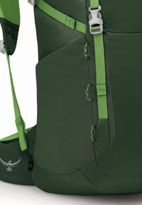 Zaino verde con tessuto testurizzato, spallacci regolabili e fibbie. Include anelli laterali e dettaglio del logo sul fondo.