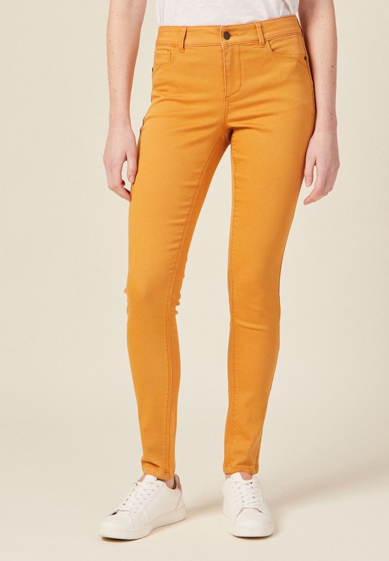 Yellow slim-fit jeans made of stretchy cotton blend fabric, featuring a front zipper, button closure, and five-pocket design.