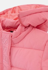 Gilet imbottito di colore rosa brillante con superficie trapuntata e testurizzata. Presenta un cappuccio e una cerniera frontale, accentuato da un logo in evidenza.
