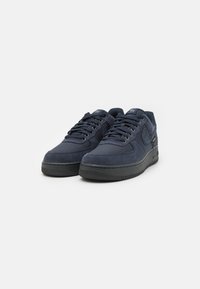 Adidași în nuanță închisă de albastru, confecționați dintr-un amestec de suede texturat și material neted, cu vârf rotund, design cu șireturi și talpă din cauciuc negru cu aderență.