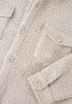 Lys grå teksturert frakk med en fluffy stoff, to brystlommer og runde knapper. Overflaten viser et mykt boucle mønster.
