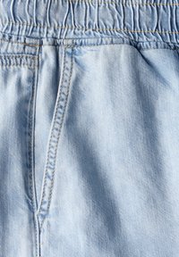 Helleblaue Denim-Hosen mit einem elastischen Bund. Verfügt über eine Fronttasche und eine glatte Textur mit sichtbaren Nähdetails.