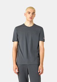 Graues Baumwoll-T-Shirt mit Rundhalsausschnitt und kurzen Ärmeln. Verf�ügt über ein kleines Logo auf der Brust und ein Logopatch am Ärmel.
