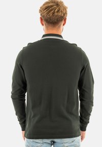Polo a maniche lunghe di colore verde scuro con colletto piatto, caratterizzato da strisce bianche, texture morbida e orlo dritto. Vista posteriore mostrata.