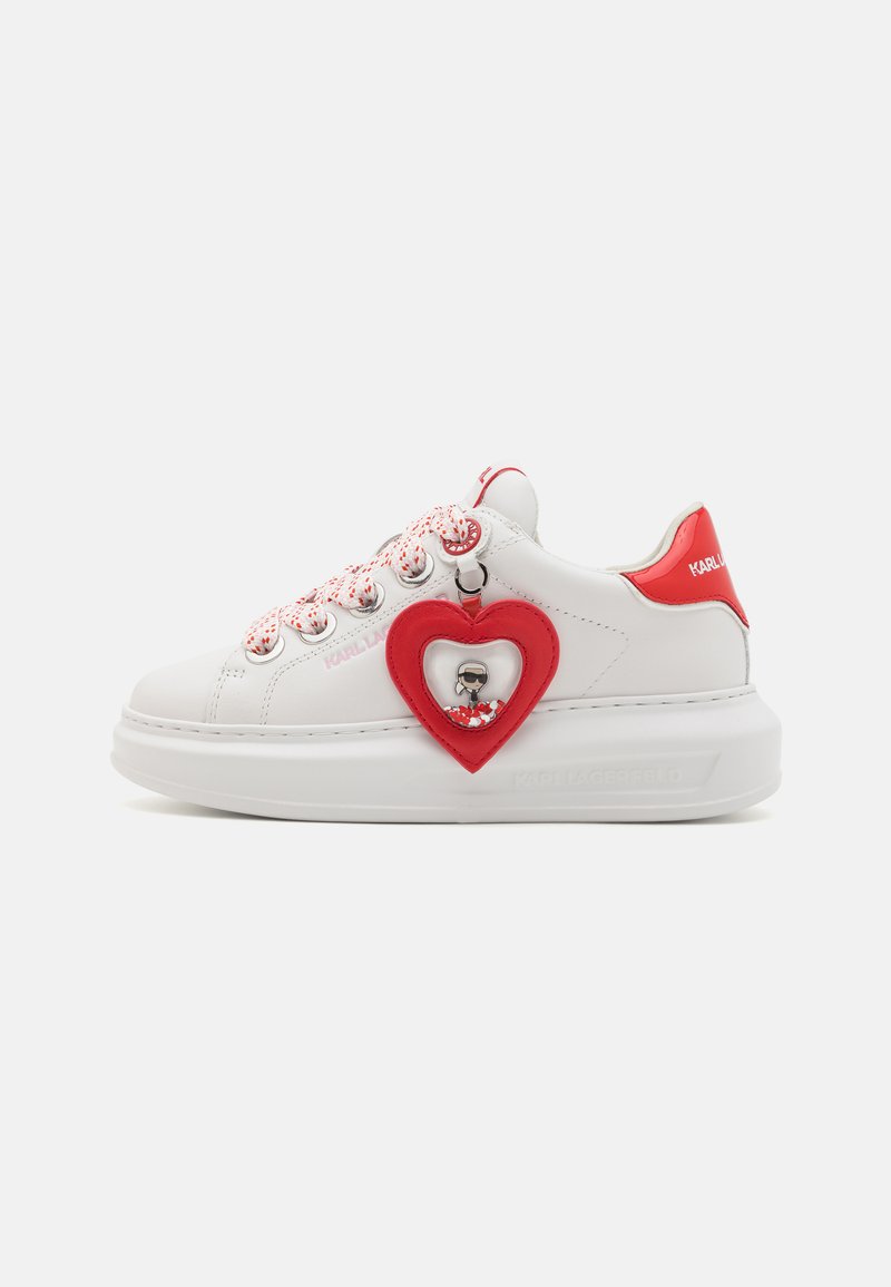 Fehér sneaker piros részletekkel, textúrált szív alakú charm, mintás fűzők és vastag fehér talp. Logó a sarokon.