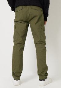 Olijfgroene cargobroek van een katoenmix, voorzien van meerdere zijzakken, elastische manchetten en een recht model.