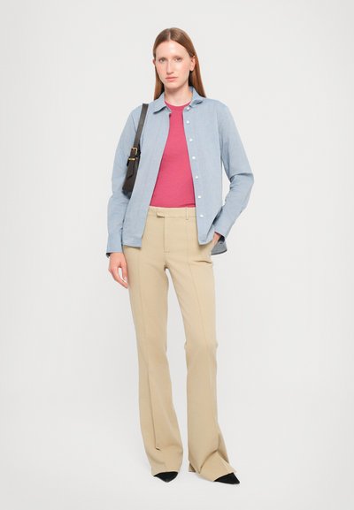 Camisa azul claro de botón, top rosa, pantalones beige, zapatos negros. Diseño simple, corte a medida, textura suave con detalles sutiles.