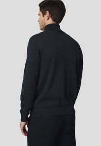 Ciemnoszary sweter z dzianiny z wysokim kołnierzem, długimi rękawami, prążkowanymi mankietami i dolną krawędzią, wykonany z miękkiego materiału, ułożony płasko na jasnym tle.