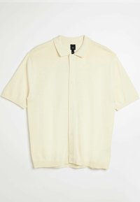 Kortärmad pikétröja i krämfärg med mjuk textur, klassisk krage och knäppning framtill. Har ribbstickad fåll och ärmar.