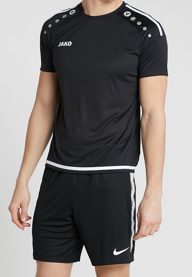 Černé sportovní tričko s šedými akcenty, které má tečkovaný design ramene. V kombinaci s černými šortkami, zdobenými bílým logem Nike.