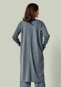 Grauer langer Cardigan mit gerippten Ärmeln, geradem Schnitt und einer Mittelnähten auf der Rückseite, aus weichem, strukturiertem Stoff.