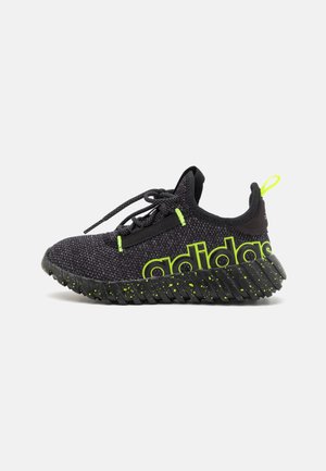 Black athletic sneaker with a textured knit upper, featuring bright green accents and a prominent logo, and a ridged, speckled outsole.