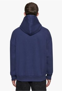 Granatowa bluza z kapturem wykonana z miękkiego materiału, z dużym kapturem, szerokimi mankietami i luźnym krojem. Prosty design bez widocznych wzorów ani akcentów.
