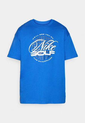 Blue short-sleeve t-shirt made from cotton, featuring a large white graphic that includes "Nike Golf" and text inside a dotted circle.