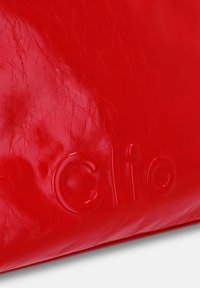 Rode leren handtas met een textuur, voorzien van het reliëf "Clio" logo. Het ontwerp is compact en glad, waardoor de levendige kleur benadrukt wordt.