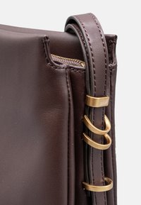 Borsa a tracolla in pelle marrone con chiusura a zip, dettagli in metallo dorato e forma strutturata con un manico dettagliato. Texture liscia.