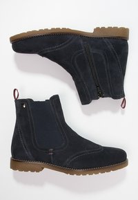 Bottines en suède navy avec zip sur le côté, panneau élastique, couture contrastante, semelle en caoutchouc et tirant. Bout rond et design robuste.