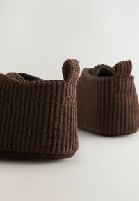 Brune strikkede tøfler med ribbet tekstur, rund form og små løkkede detaljer øverst. Blødt indre for og polstret sål.