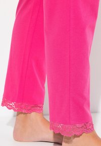 Rosa Baumwoll-Schlafanzughosen mit Spitzenbesatz am Saum, die eine glatte Textur und eine lockere Passform bieten.