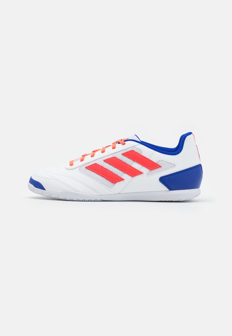 Witte sportshoe met oranje accenten en blauwe details. Heeft een drie-stripe ontwerp, veters, een gestructureerde bovenkant en een rubberen zool.