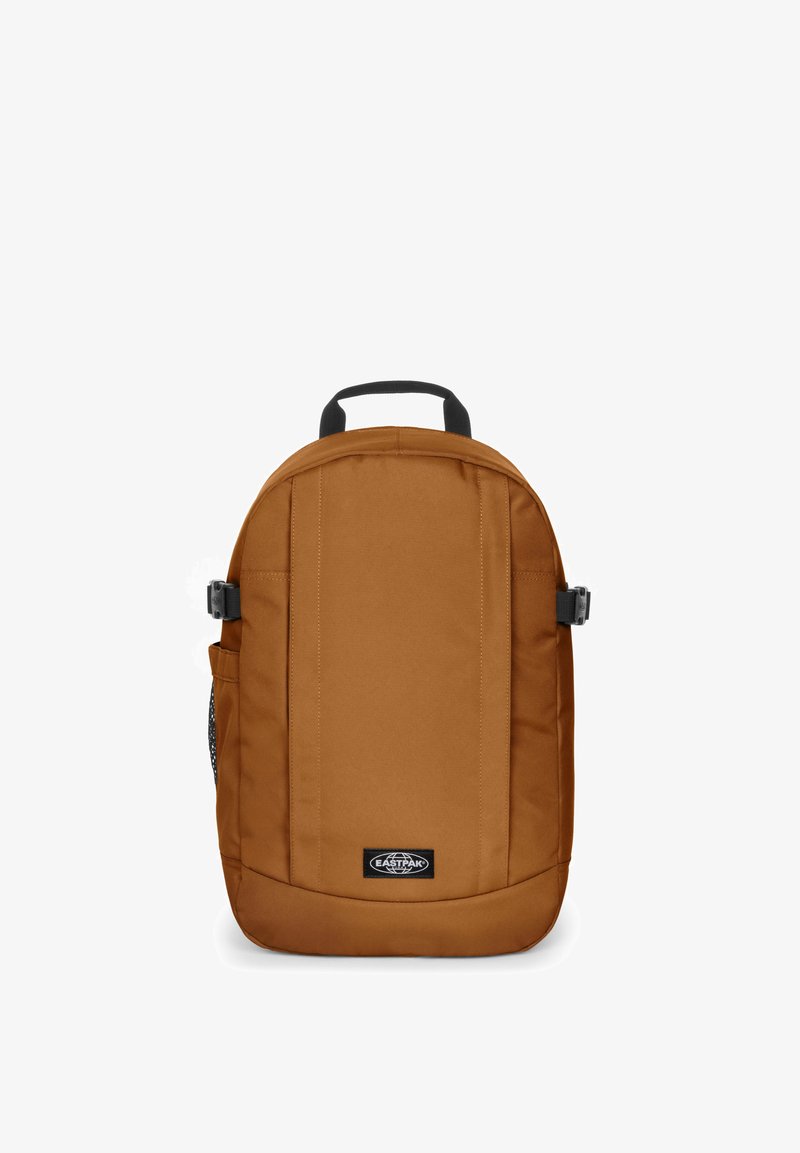 Brązowy plecak z gładką powierzchnią, okrągłym kształtem, górnym uchwytami, boczną siateczkową kieszenią oraz regulowanymi paskami. Zawiera naszywkę z logo.