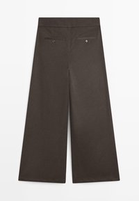 Bruine wijde broek gemaakt van gladde stof. Heeft een platte tailleband, twee achterzakken met knoopsluitingen en gestikte zomen.