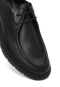 Scarpa in pelle nera con finitura liscia, punta tonda, dettagli cuciti e lacci neri. Presenta una suola in gomma testurizzata per una buona aderenza.