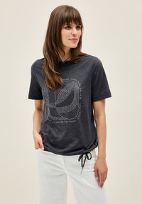 Dark gray t-shirt made of soft fabric, featuring a leaf pattern and a decorative print with text in white. Relaxed fit with short sleeves.