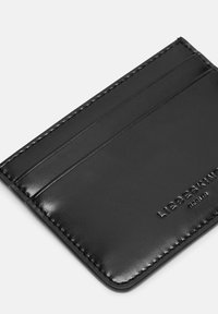 Czarny skórzany portfel na karty z czterema przegródkami, gładką fakturą, widocznym przeszyciem na krawędziach oraz wytłoczonym logo marki na jednej stronie.