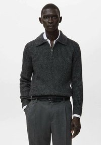 Ciemnoszary sweter z prążkowanego dziania z zamkiem przy kołnierzu, zestawiony z szarymi spodniami i białą koszulą z kołnierzykiem, prezentujący teksturowaną tkaninę.