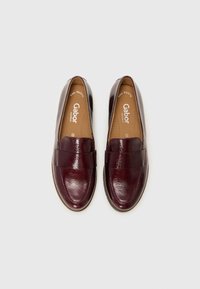 Burgundijas ādas loafers ar gludu tekstūru, ar plašu joslu pāri augšai, mīkstu iekšējo zoli un noapaļotu pirksta dizainu.