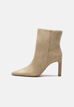 Bottine beige en daim à bout pointu, talon bloc haut et fin, finition lisse.