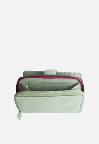 Portafoglio verde in pelle con un accento bordeaux con cerniera, multiple fessure per carte e una texture liscia. Presenta una chiusura a scatto e un compartimento con cerniera.